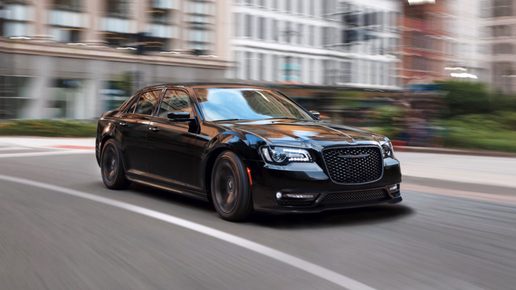 Black Chrysler 300 sedan driving through a city street