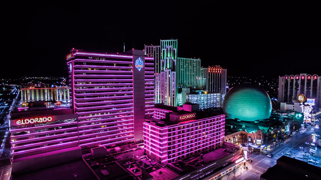 Casino towers lit in pink and green above downtown Reno at night