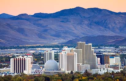Downtown Reno skyline and the Sierra Nevada foothills at dusk